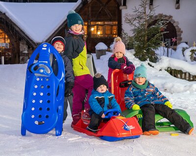 Kinder mit Schlitten vor der Tannenmühle