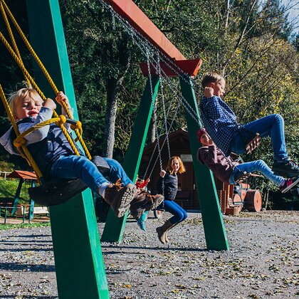 Kinder schaukeln am Spielplatz