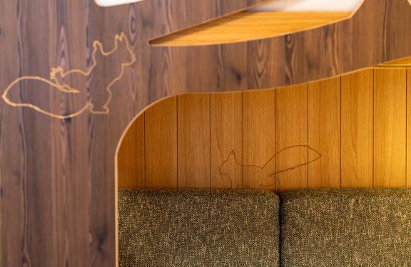 Holzvertäfelung mit eingraviertem Eichhörnchen über einem grauen Sofa
