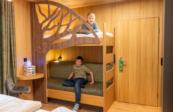 Zwei Jungen in einem Kinderzimmer mit Etagenbett aus Holz und Baumdesign